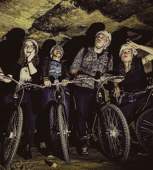 jonge mensen kijken gek terwijl ze met hun mountainbike in de hand naar het plafond in de grotten kijken
