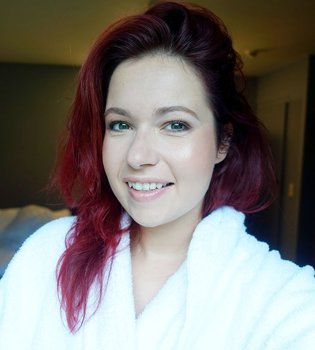 Selfie van een dame in witte badjas en rood haar. 
