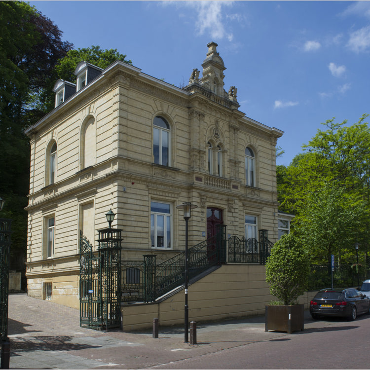 Villa van mergel met trapjes ervoor in een pittoreske dorpsstraat. 