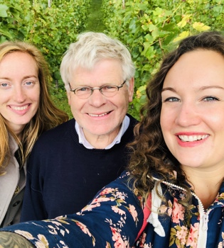 Twee dames en een oudere heer maken een selfie in de wijngaard