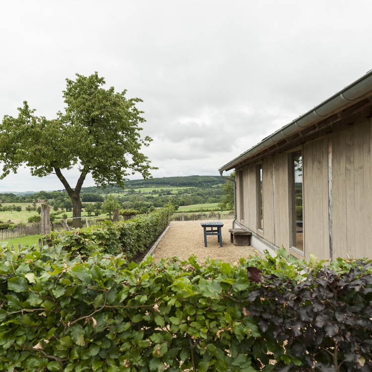 Houten vakantiewoning met een aangrenzend terras en uitzicht over het heuvelland. 