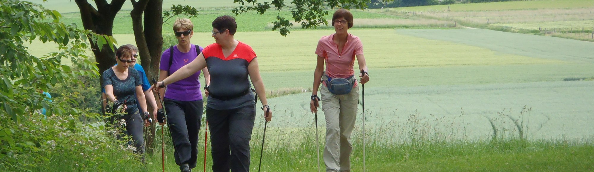 een groep vrouwen loopt door een grasveld een heuvel op
