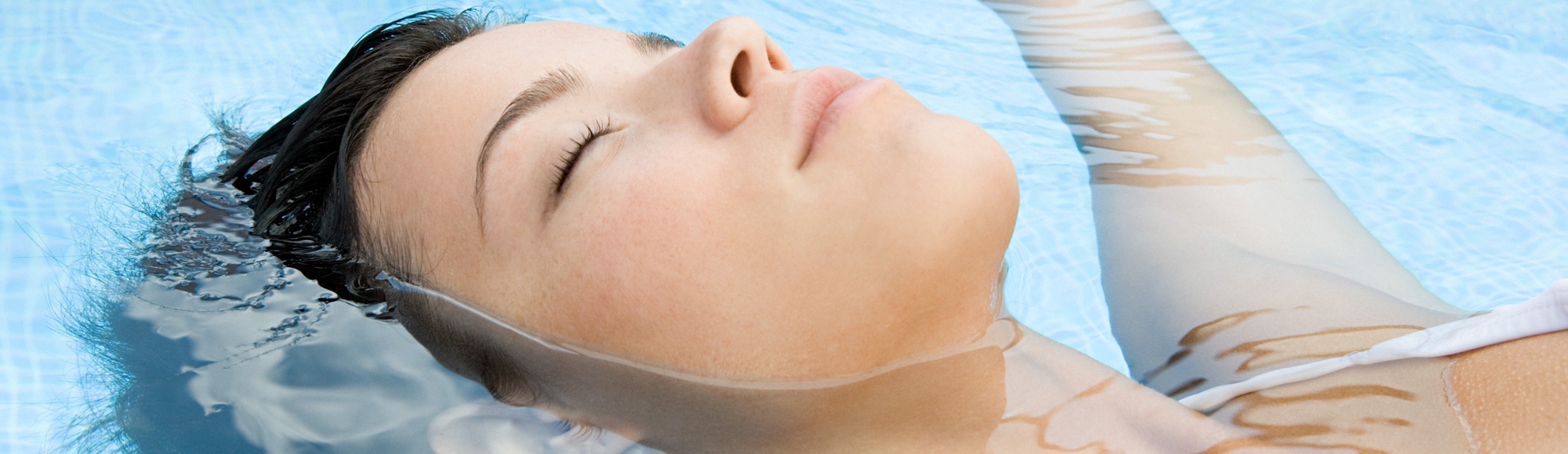 Vrouw ligt te ontspannen in een zwembad met de ogen dicht. 