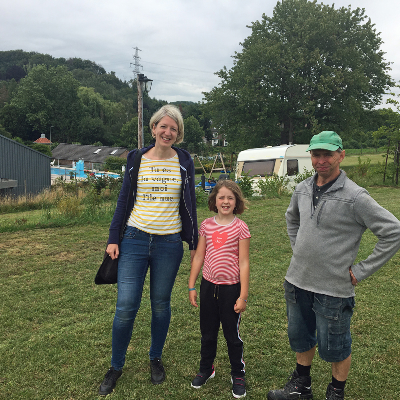 Gezin poseert op een grasveld op de camping. 