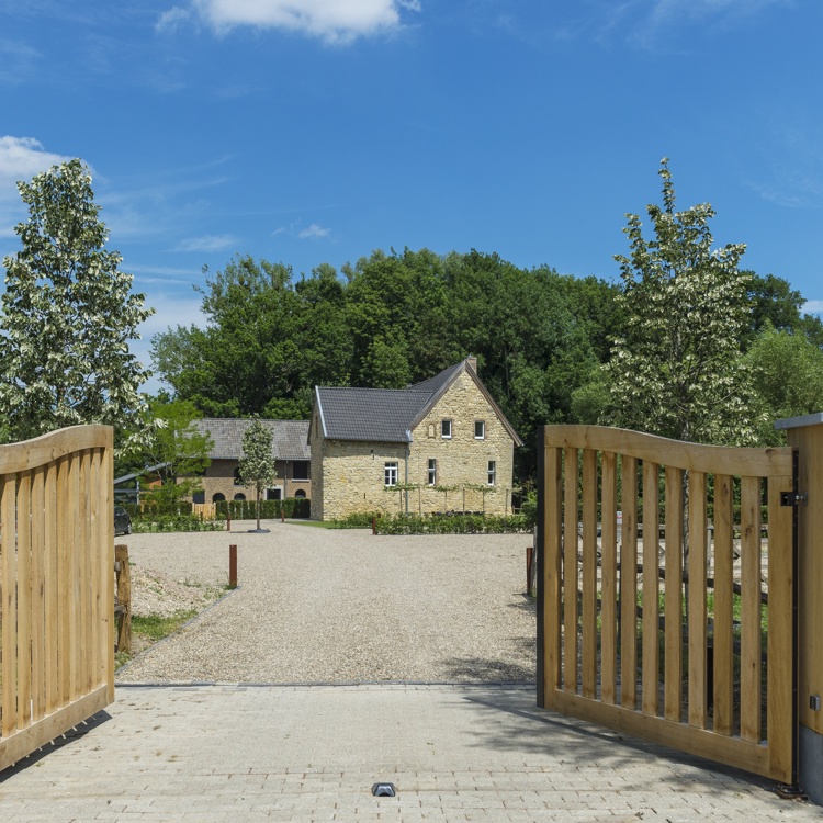 Houten openslaande poort met in de verte een vakantiewoning van mergel