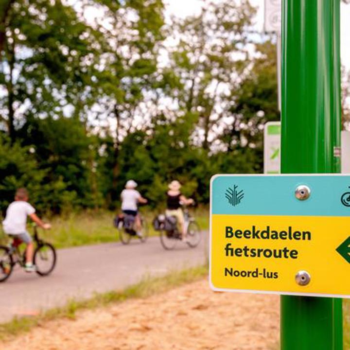Bewegwijzering Beekdaelen fietsroute met fietsers op de achtergrond