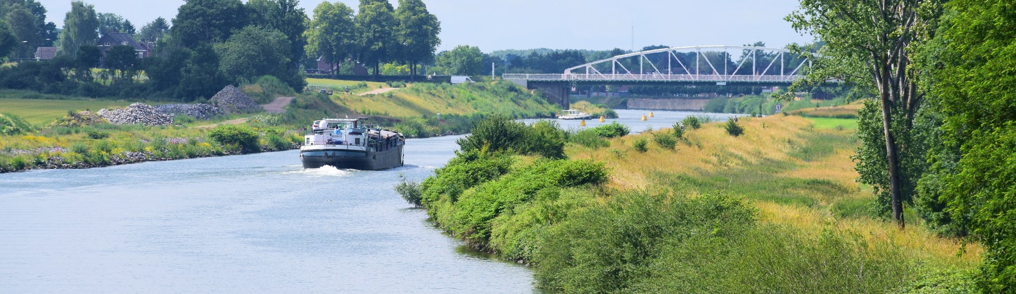 Vrachtschip met groen landschap en brug