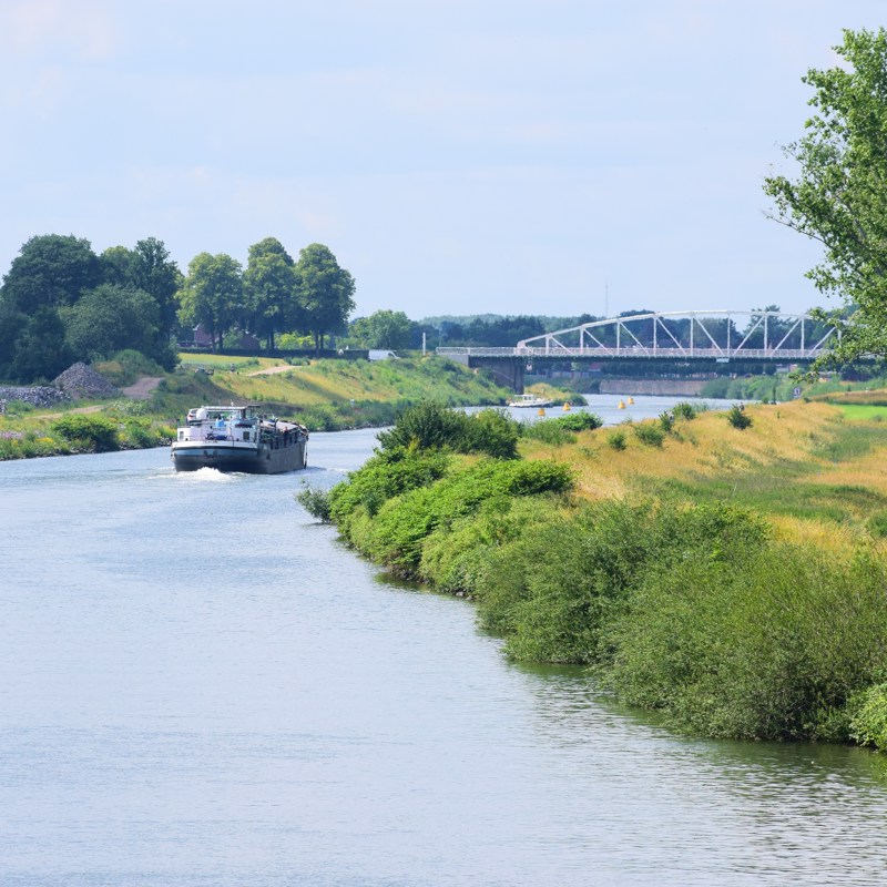 Vrachtschip met groen landschap en brug