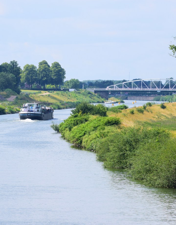 Vrachtschip met groen landschap en brug