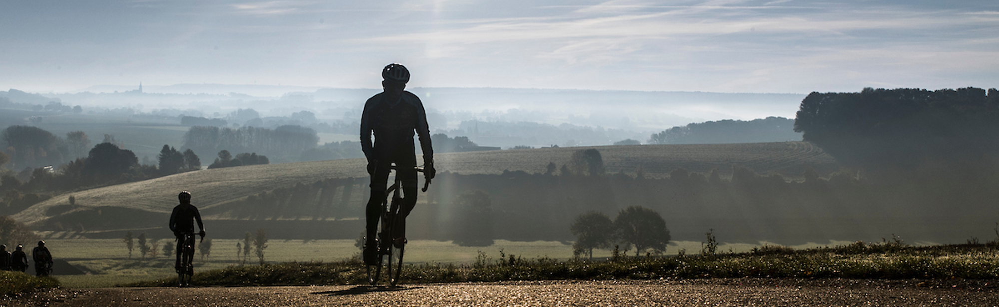 Wielrenners fietsen berg op met een prachtig uitzicht op het landschap en een laagstaande zon