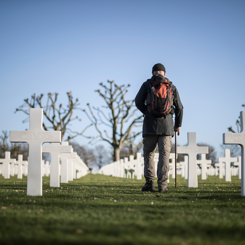 Man met stok loopt door de Amerikaanse Begraafplaats