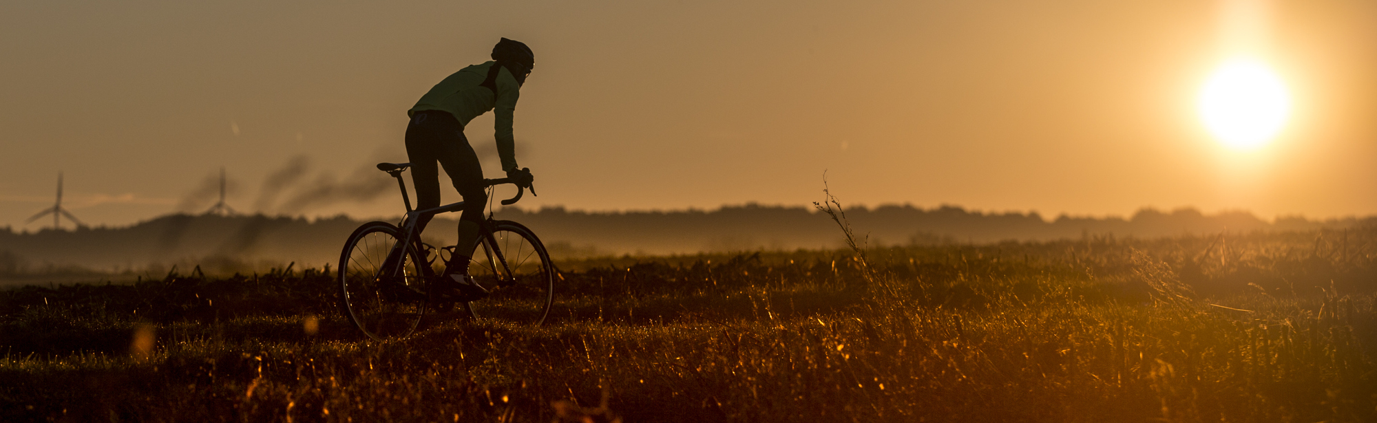 Wielrenner fietst een heuvel op met zonsondergang