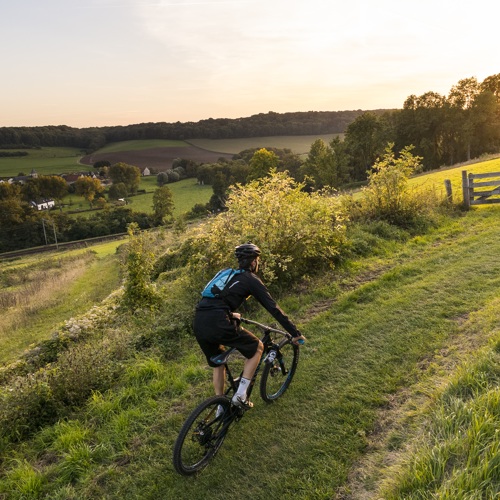 Mountainbiker fietst bergje op met zonsopkomst