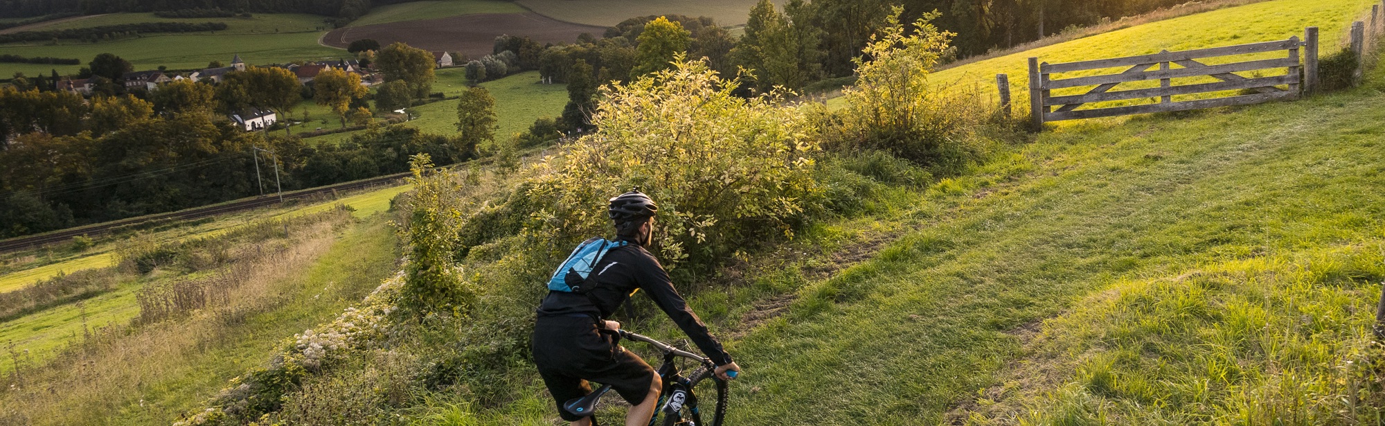 Mountainbiker fietst bergje op met zonsopkomst