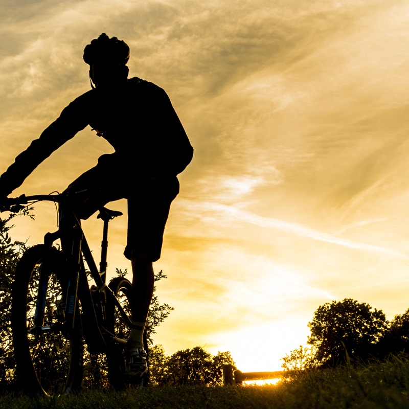 Mountainbiker met een lage zon achter zich