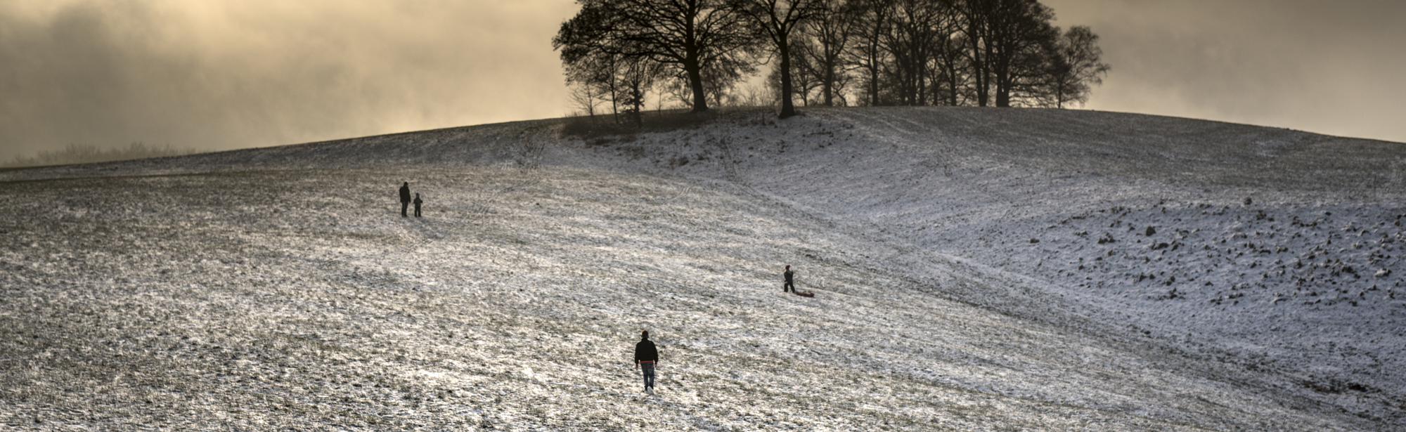 Uitgestrekte heuvels met een laagje sneeuw en een paar wandelaars