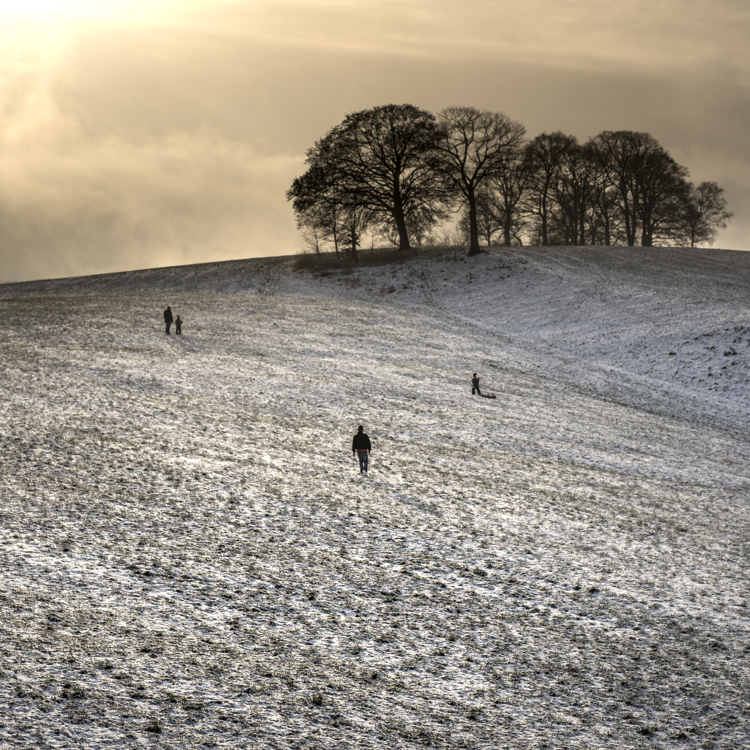 Uitgestrekte heuvels met een laagje sneeuw en een paar wandelaars