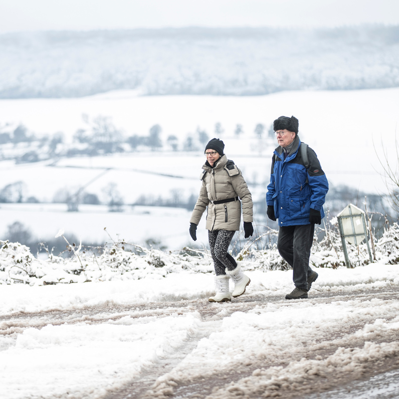 Twee wandelaars wandelen in een winterwonderlandschap met uitzicht over de witte heuvels