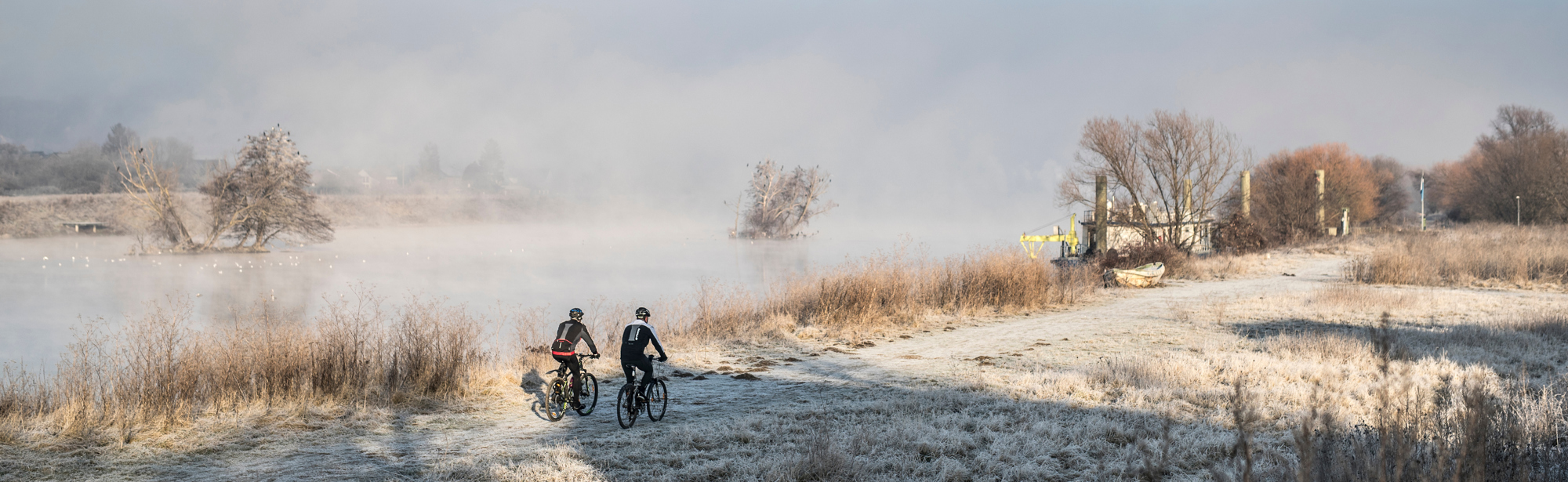 Mountainbiken in een winters landschap langs een mistige rivier