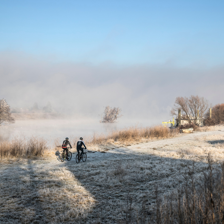 Mountainbiken in een winters landschap langs een mistige rivier