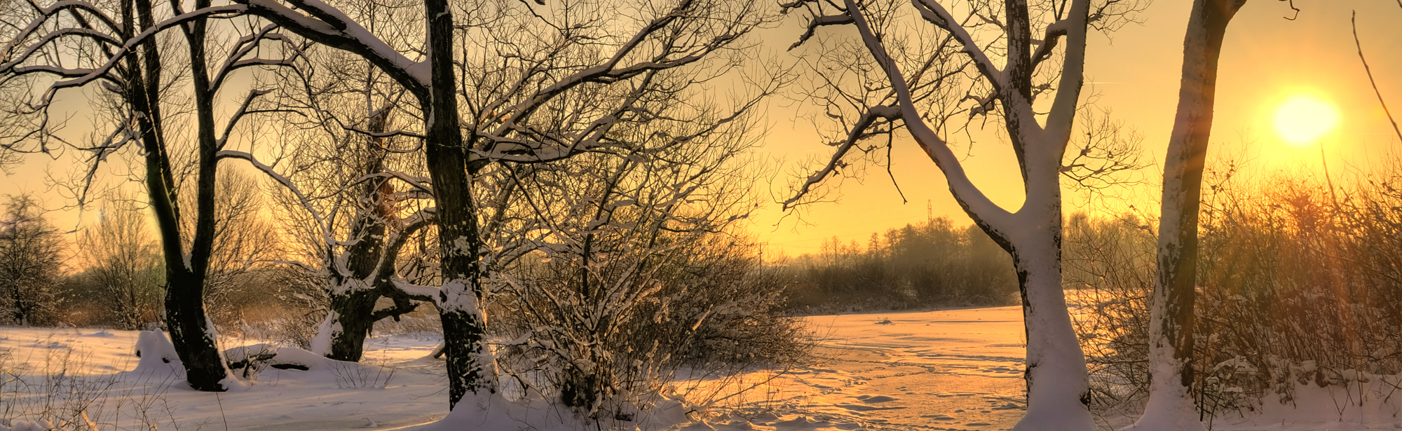 Een winters landschap met felle zon bij zonsopkomst