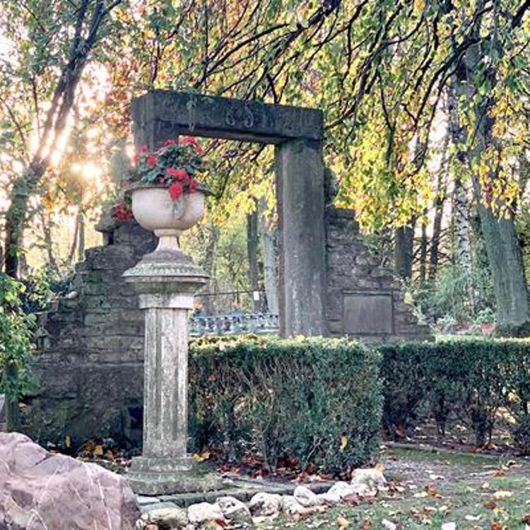 Grote steen met plant op zuil en stenenpoort bij Stiltetuin Bemelen