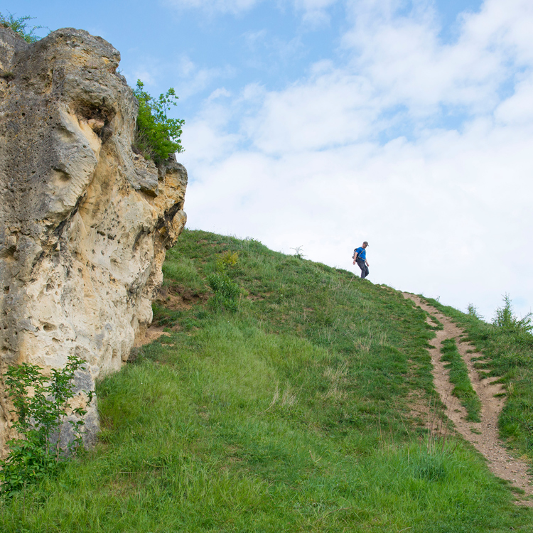 Een man met rugzak daalt een steile weg naar beneden bij de Duivelsgrot