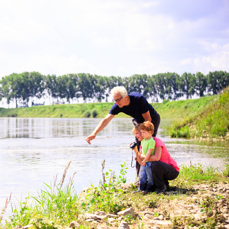 Een kindje kijkt met zijn opa en oma naar het water in de Maas