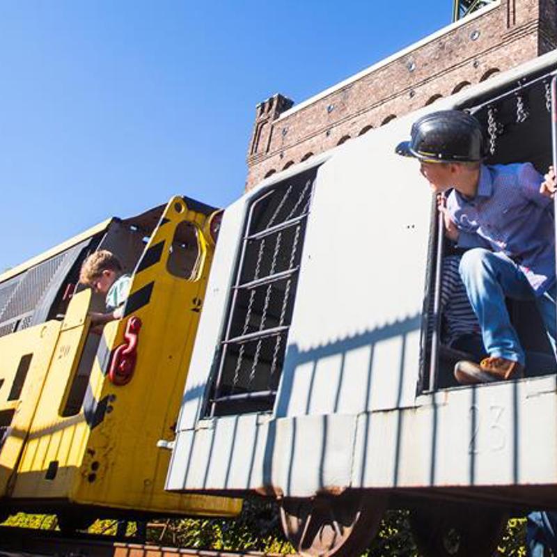 Twee kinderen spelen in een stilstaande treinwagons voor de Schacht in Heerlen