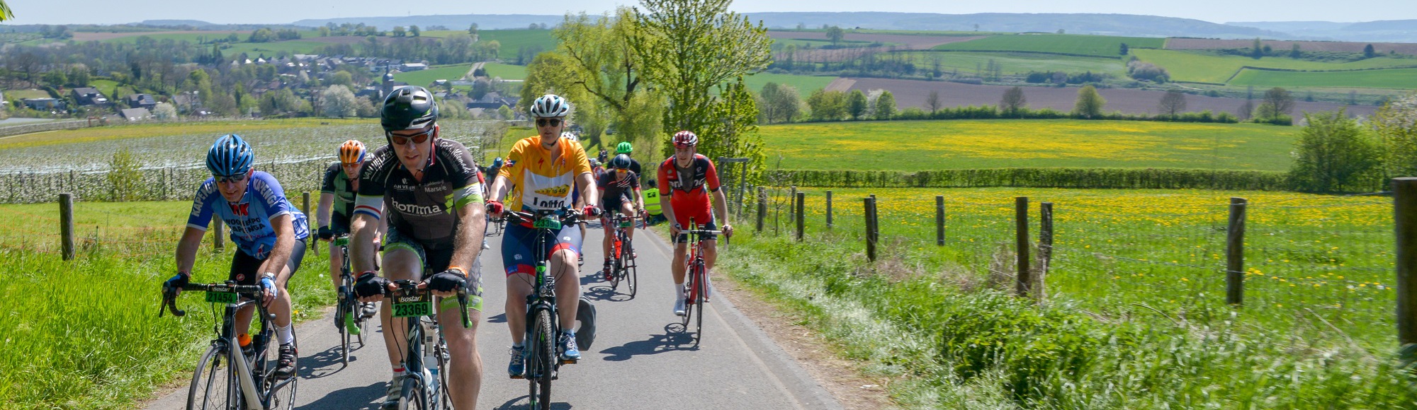 Wielrenners beklimmen een berg met mooi uitzicht op de achtergrond tijdens de Amstel Gold Toerversie