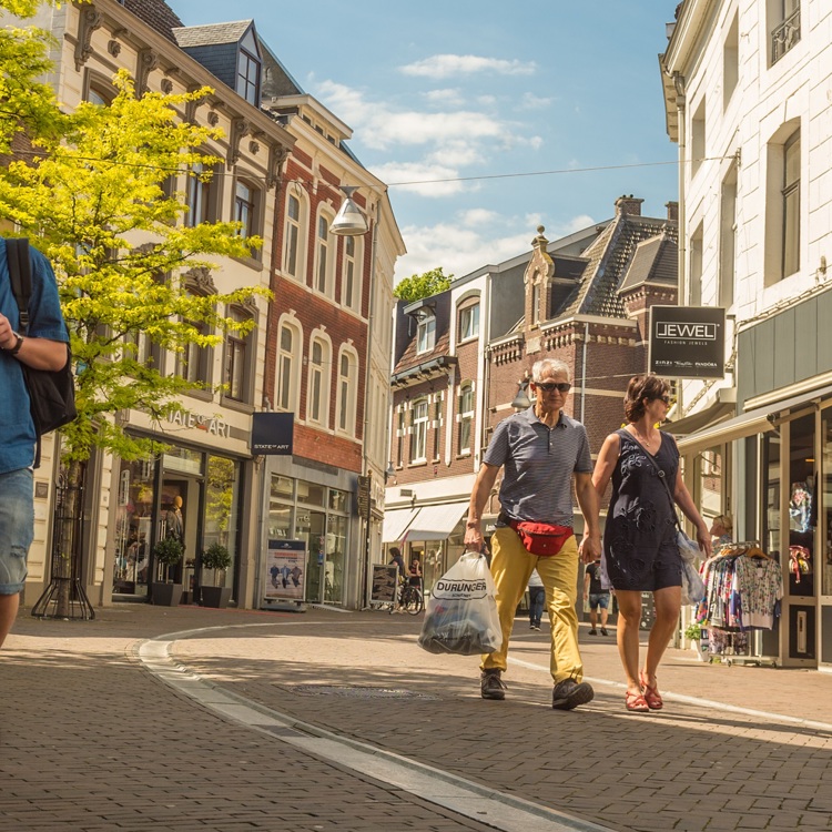 Een koppel en een jongeman lopen door de winkelstraten van Sittard op een zonnige dag