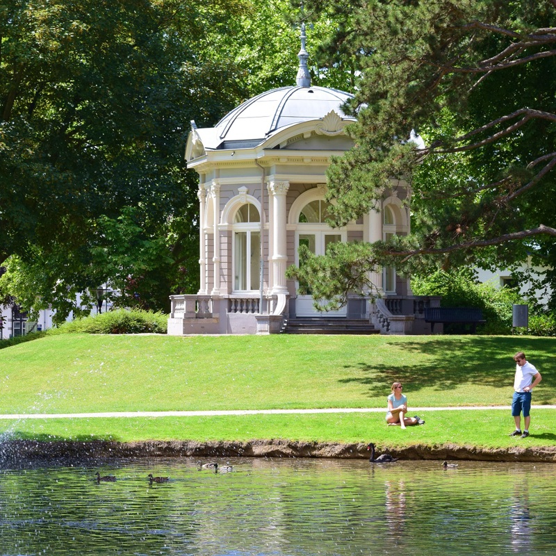 Het Proosdijpark in Meerssen met een prieeltje en twee mensen die genieten van het zomerse weer