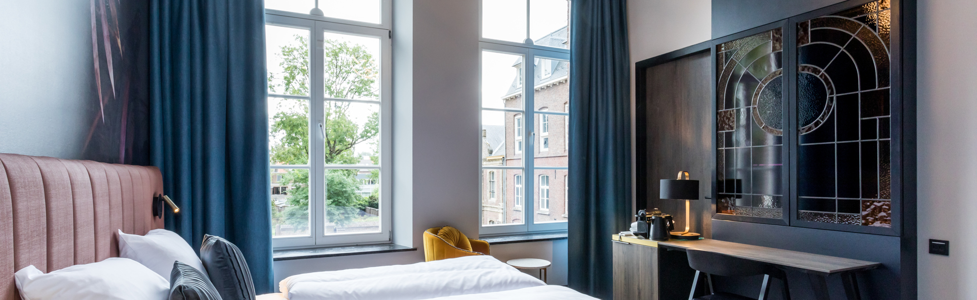 Sfeervolle hotelkamer met tweepersoonsbed en een werkplek. 