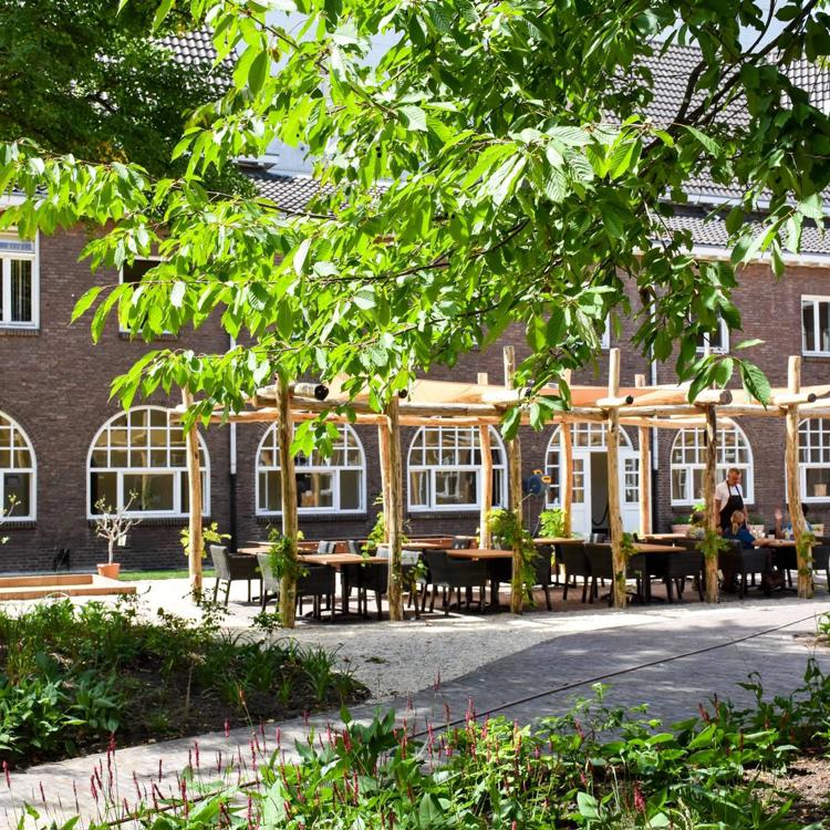 Een knus terras op het binnenplein van een oud kloostergebouw omringd door moestuin