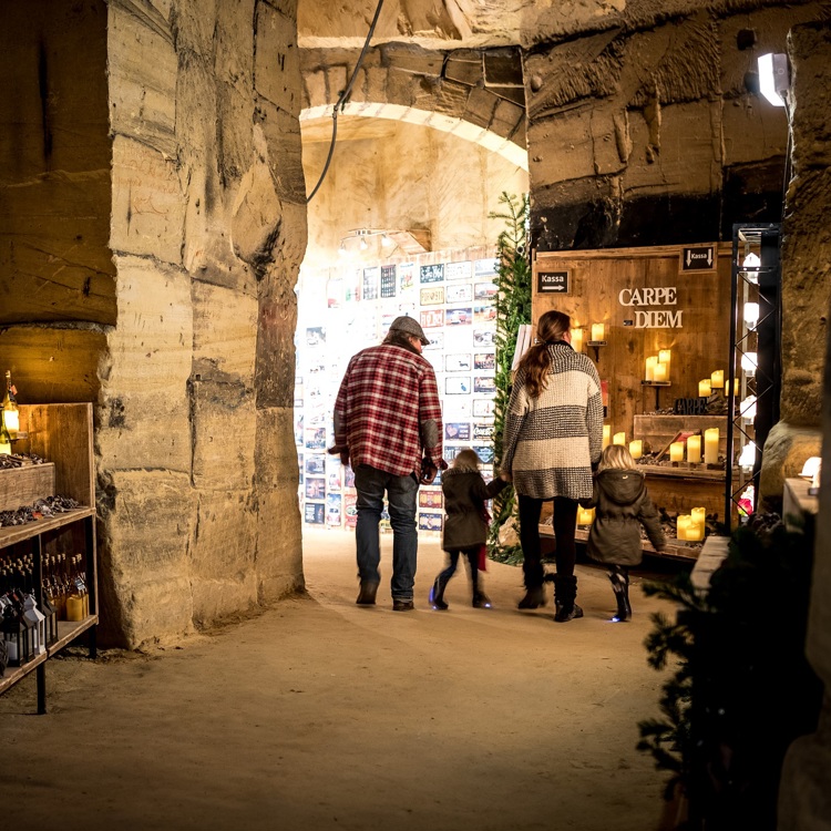 Gezin loopt door gangen tijdens Kerstmarkt Flueweelengrot