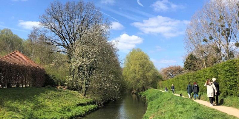 Mensen wandelen in het zonnetje op een frisse lentedag langs de Geleenbeek