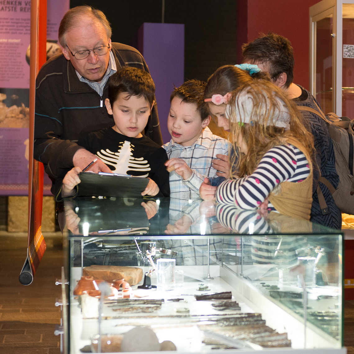 Kinderen en oudere meneer bekijk overblijfselen van de Romeinse tijd in het museum De Vondst