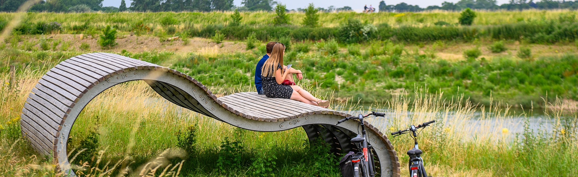 Een koppel pauzeert op een kunstwerk langs de Maas