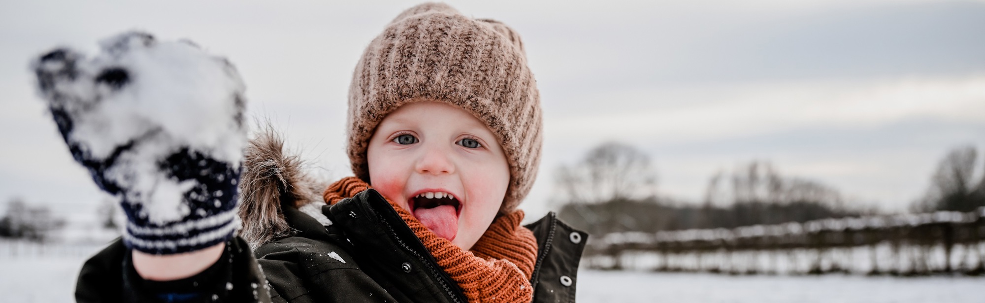 Ondeugend jongetje gooit een sneeuwbal richting de camera