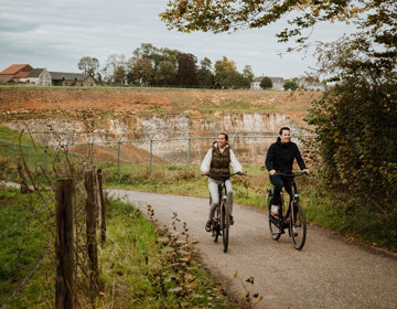 Herfstige setting waarbij een koppel naast elkaar fiets en waarbij je op de achtergrond groeve 't rooth ziet liggen