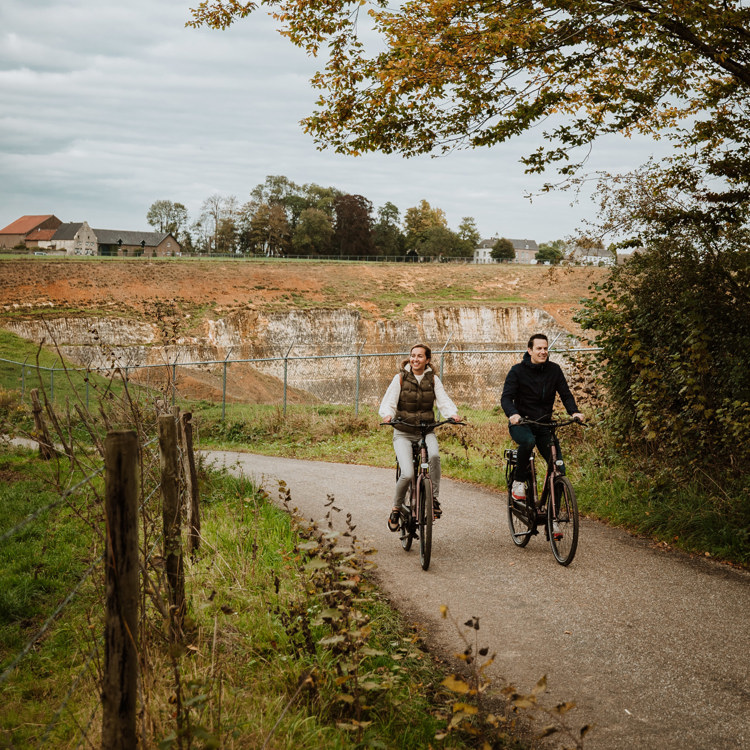 Herfstige setting waarbij een koppel naast elkaar fiets en waarbij je op de achtergrond groeve 't rooth ziet liggen