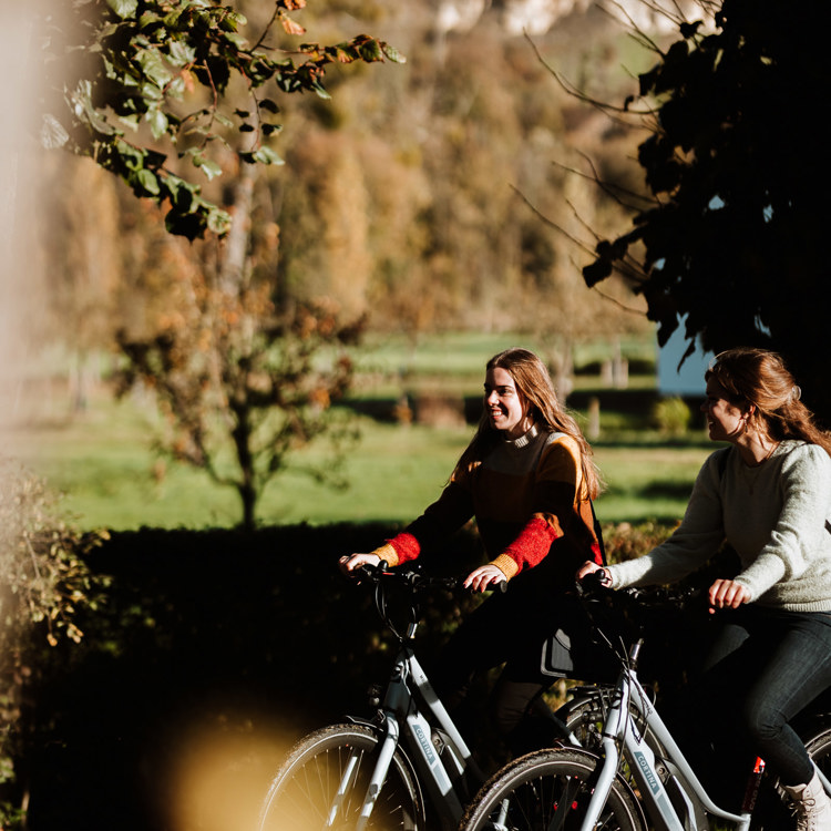 Twee dames lachend op de fiets naast elkaar, met Uitzicht Op Daolkesberg