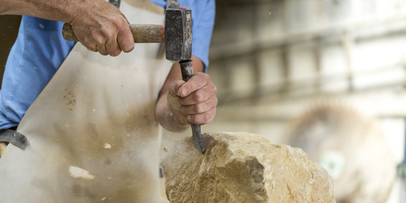 Persoon is bezig met het bewerken van mergel met gereedschap in zijn handen. 