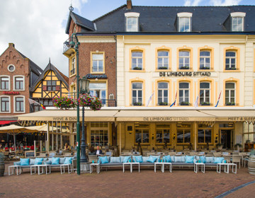 Vooraanzicht van het terras en het gele gebouw van de Limbourg op de markt in Sittard