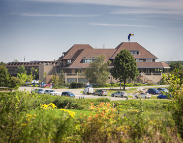 Het Van der Valk hotel in Urmond met geparkeerde auto's en natuur