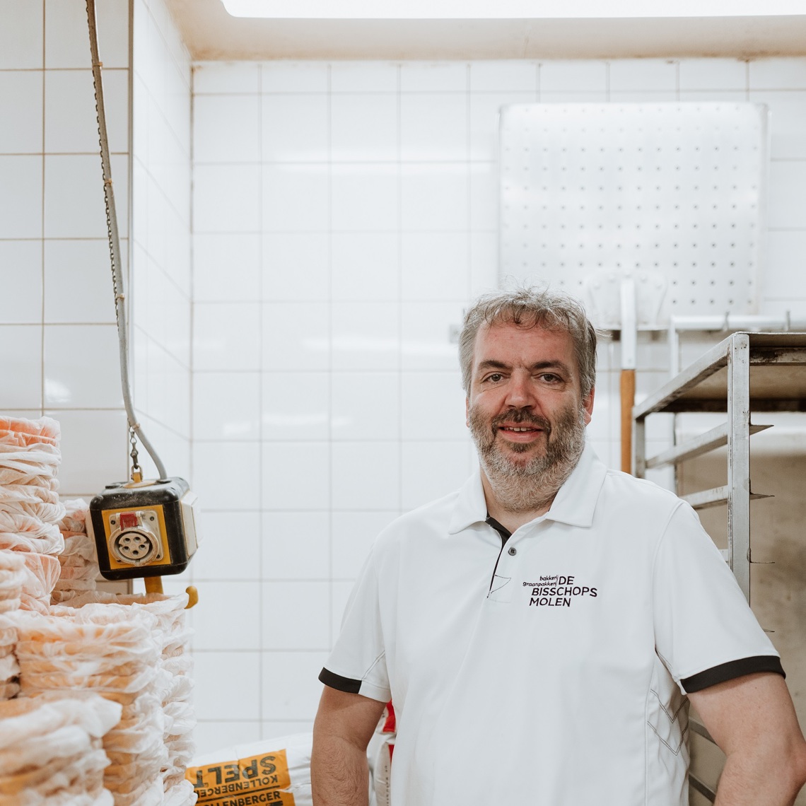 Frank van Eerd poseert in zijn bakkerij voor de zakken met speltmeel