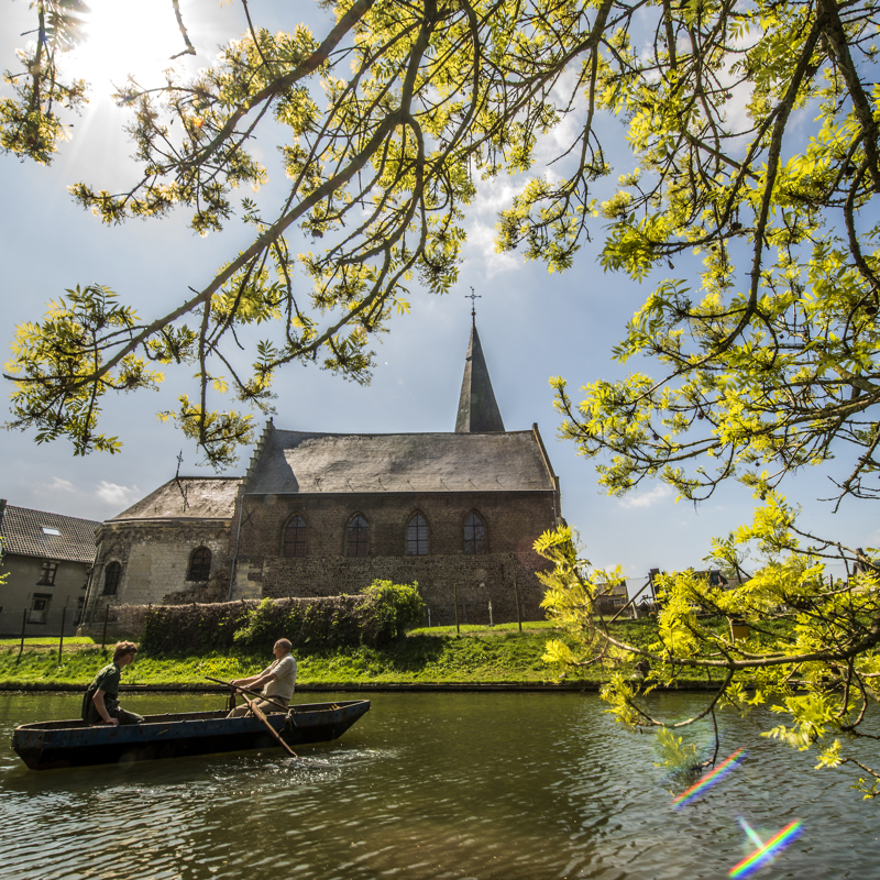 Zicht op het Salvius kerkje Limbricht vanaf een bootje in de grachten van Kasteel Limbricht