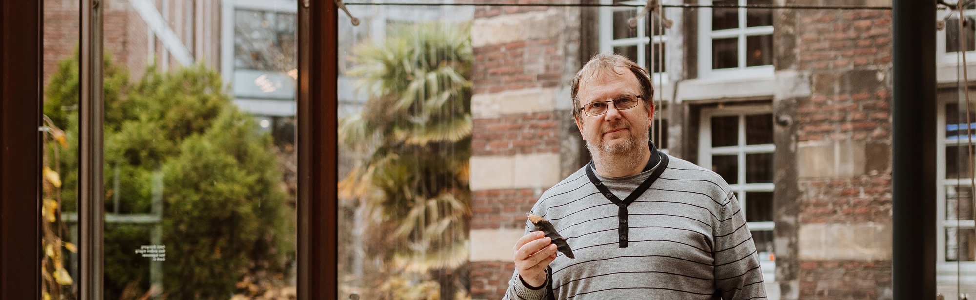 Joep Orbons poseert in een museum met een prehistorische steen in zijn hand