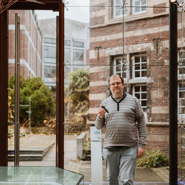 Joep Orbons poseert in een museum met een prehistorische steen in zijn hand