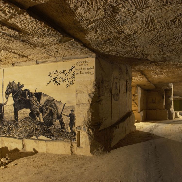 foto gemaakt in de grot waarin je een tekening met een paard ziet aan de muur, en rechts doorkijkt naar andere grotgangen.